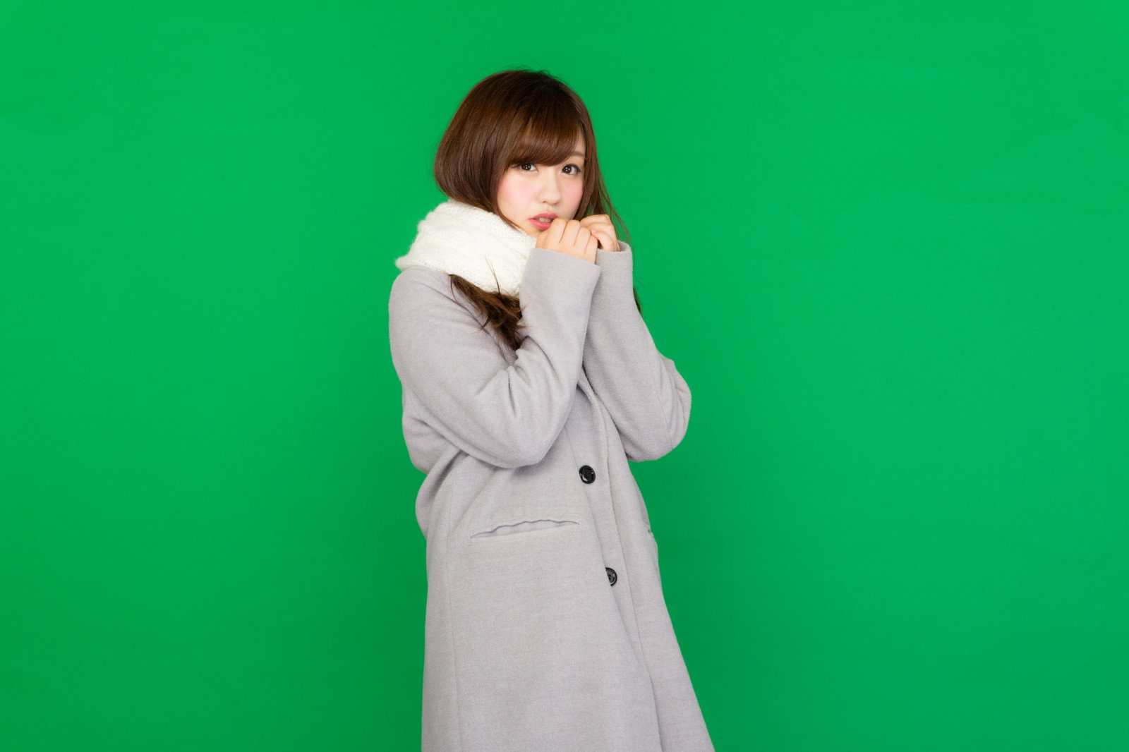グリーンバック前でマフラーとファー襟コートを着てポーズをとる女性［モデル：河村友歌］