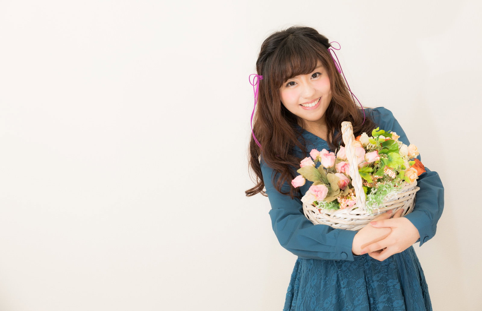 フラワーバスケットを抱えて笑顔の女性［モデル：河村友歌］