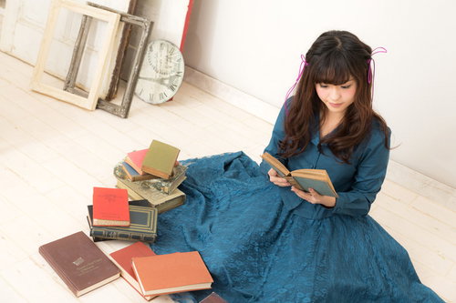 花柄レースのスカートで読書する女性とたくさんの本