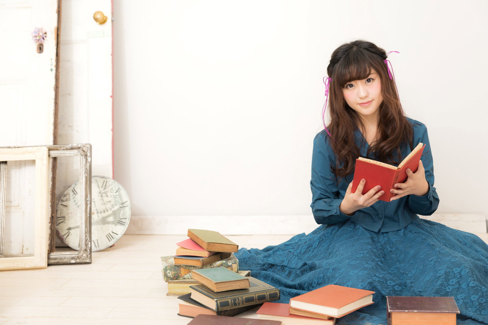 本に囲まれて赤い本を読む女性［モデル：河村友歌］
