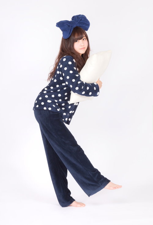 白い枕を抱えたネイビーのドット柄パジャマ姿の女性