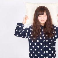 ぐっすり快眠する水玉パジャマの女性のガッツポーズの写真