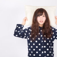 寝すぎて遅刻ギリギリ、枕を持って驚く女性の写真