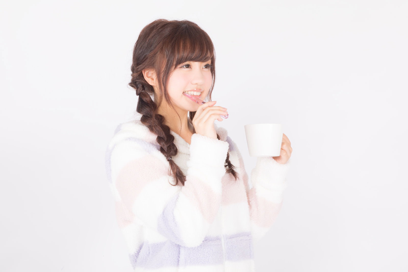 白いパジャマを着た若い女性が歯ブラシで歯を磨いている［モデル：河村友歌］