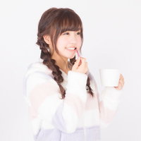 スマホを見て笑う三つ編みの女性の写真