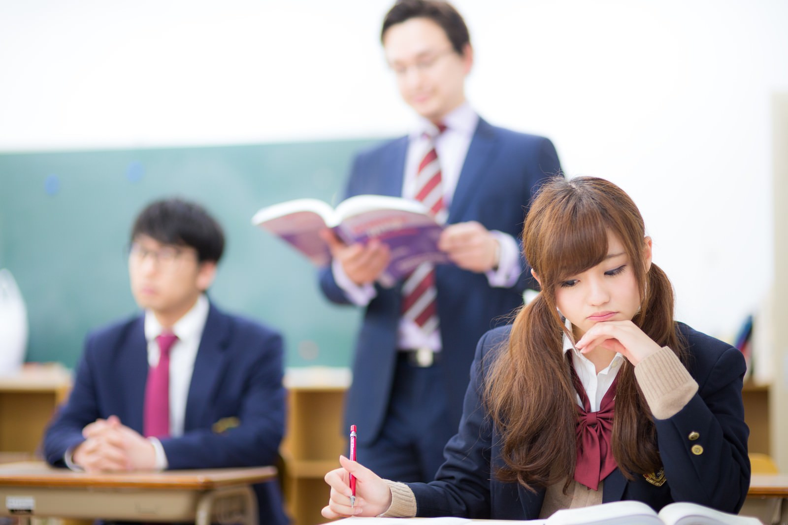 教室で授業を受ける高校生。手前の女子生徒は勉学に集中し、奥の男子生徒は考え込んでいる［モデル：Max_Ezaki 河村友歌 大川竜弥］