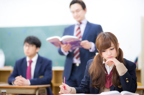 勉学に励む女子生徒と授業中に考え込む男子生徒。学校生活における学力差