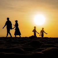 夕暮れの浜辺を行き交う人々のシルエット、夕日と砂浜の写真