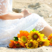 砂浜で花束を抱きしめ想い出に浸る白いドレスの女性の写真