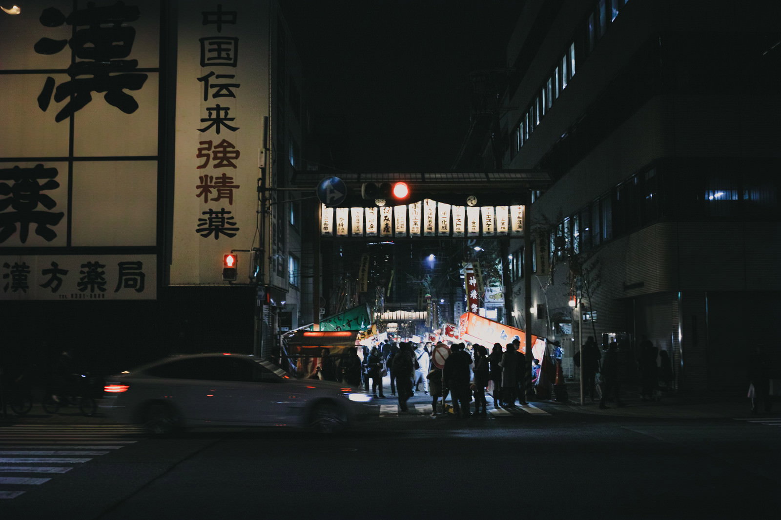 提灯が灯る夜の商店街で祭りを楽しむ多くの人々