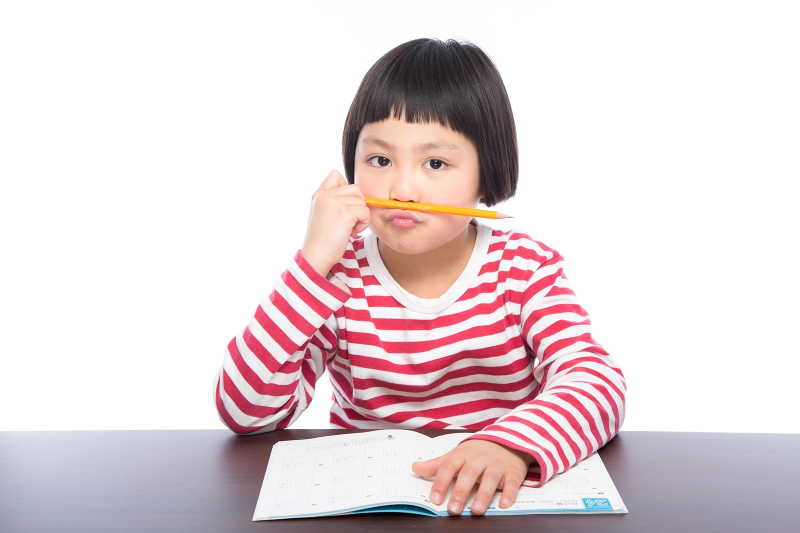 赤白ボーダーシャツの子どもが鉛筆をくわえて宿題をしている［モデル：ゆうき］