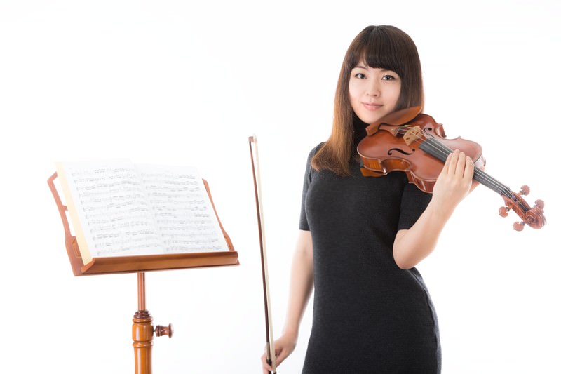 ヴァイオリンを演奏中の女性・黒い衣装で集中する演奏家の写真素材