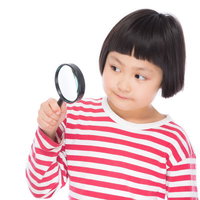 虫眼鏡で何かを調べる前髪パッツンの小学生の写真