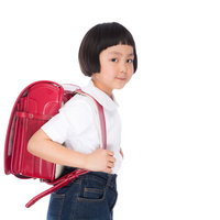 赤いランドセルを背負った前髪パッツンの小学生低学年の写真