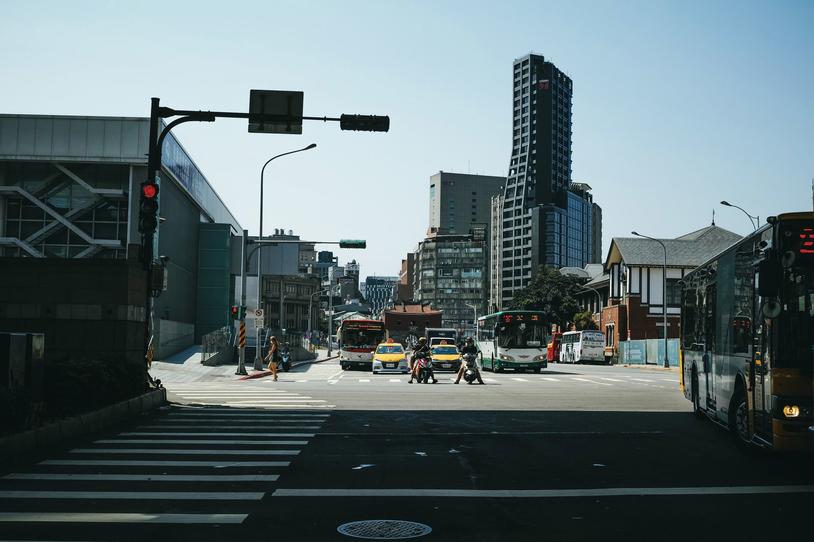 台北の交差点で信号待ちする複数の車とバイクが写る都市風景