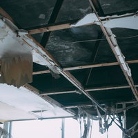 老朽化した建物で崩れ落ちる天井と傾いた柱の写真