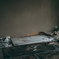 腐りかけた畳の上に置かれた古い机がある廃墟の写真