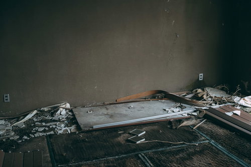 腐りかけた畳の上に置かれた古い机がある廃墟