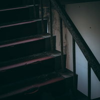 赤く暗い廃墟の階段室の風景、古いコンクリート製階段と手すりの写真