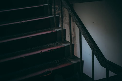 赤く暗い廃墟の階段室の風景、古いコンクリート製階段と手すり