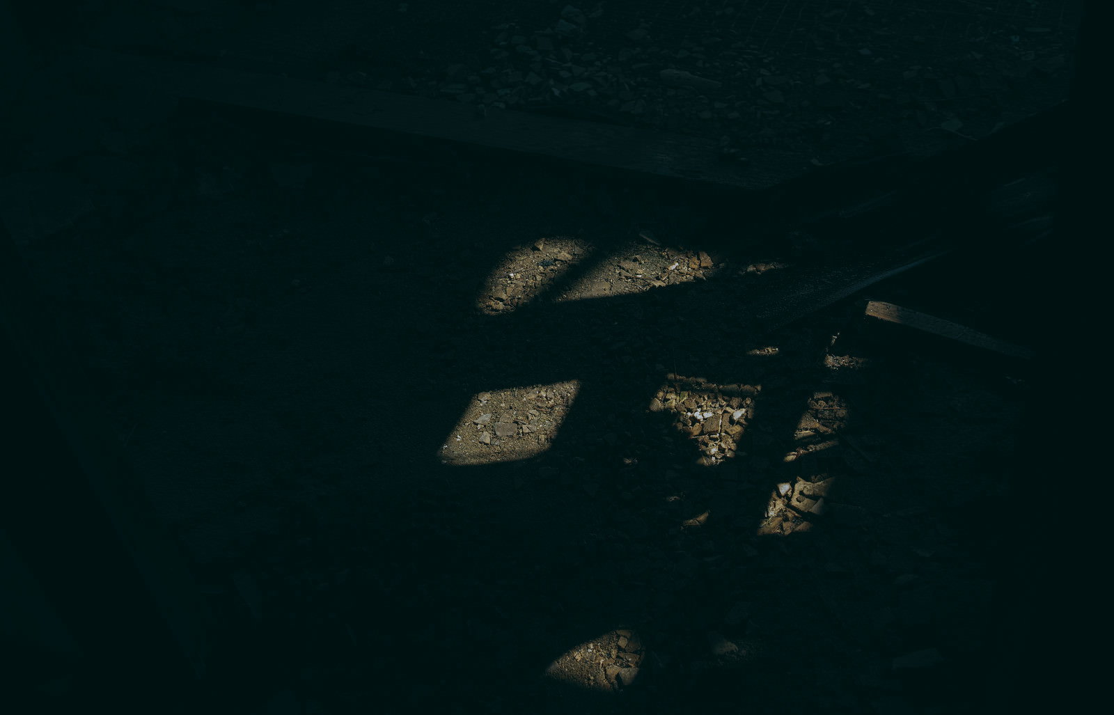 暗闇の中でわずかな光に照らされて浮かび上がる瓦礫や石の破片
