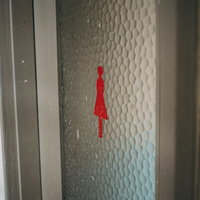 廃墟の女子トイレの扉に貼られた赤い女性マークの写真