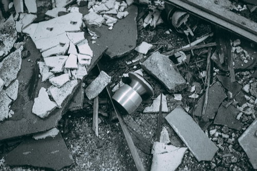 廃墟に散乱する錆びたドアノブと瓦礫、破壊されたコンクリート破片