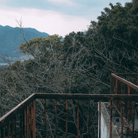山を背景にした屋上の壊れゆく鉄柵と経年変化の写真