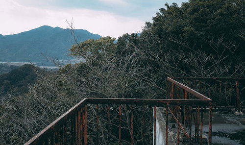 山を背景にした屋上の壊れゆく鉄柵と経年変化