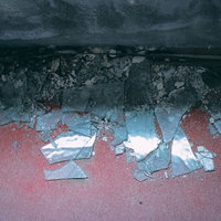 床に散らばった割れたガラス片と破片の危険な状態の写真