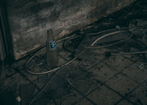 廃墟の床に飛散するガラス片と空瓶の風景