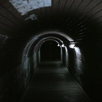 仄暗いトンネルの地下通路、石造りの壁に囲まれた細長い通路の写真