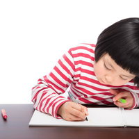 夏休みの自由課題でお絵かきに取り組む女の子の写真