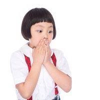 両手で口を塞ぎ驚いた表情で何かを見つめる小学生女の子の写真