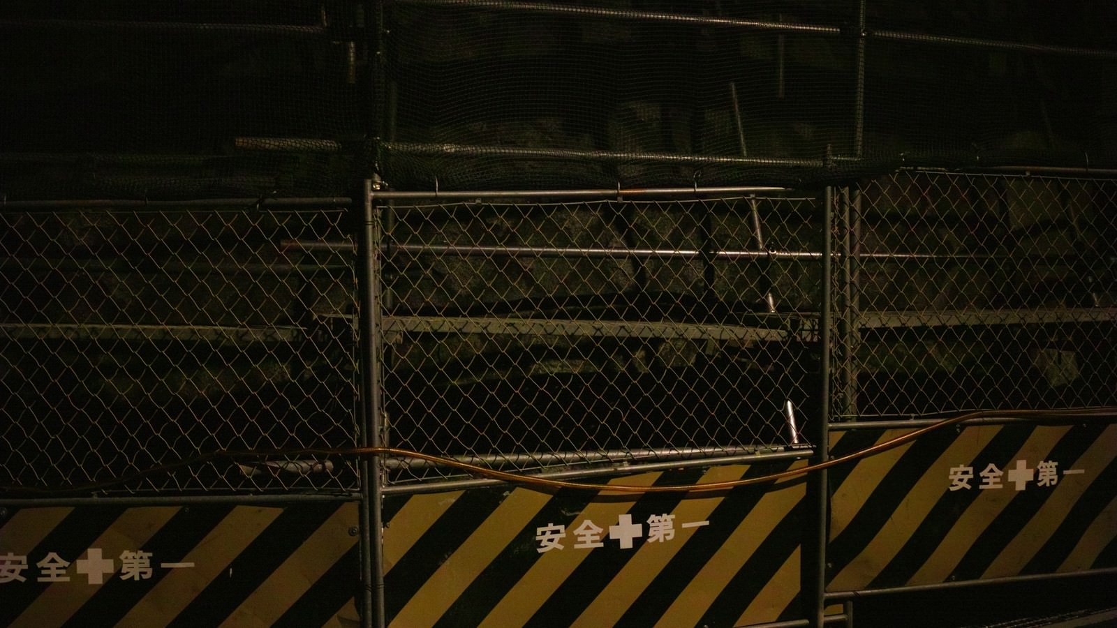 夜間の工事現場のフェンス。黒と黄色の安全第一表示と立ち入り禁止を示す警告マーク