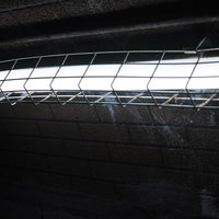 薄暗い照明が照らす不気味な壁面と金属製格子の工業施設の写真