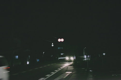 夜間走行する車のヘッドライトが車道を照らす