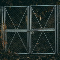 いまにもゾンビが押し寄せてきそうな金属製フェンス門扉の写真