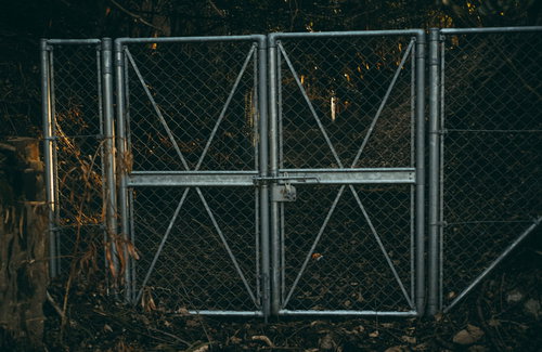 いまにもゾンビが押し寄せてきそうな金属製フェンス門扉