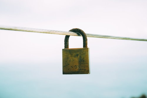 鉄線にかけられた錆びた南京錠と約束