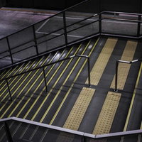 誰もいない夜の駅構内階段、蛍光灯と黄色い安全線が照らす地下通路の写真