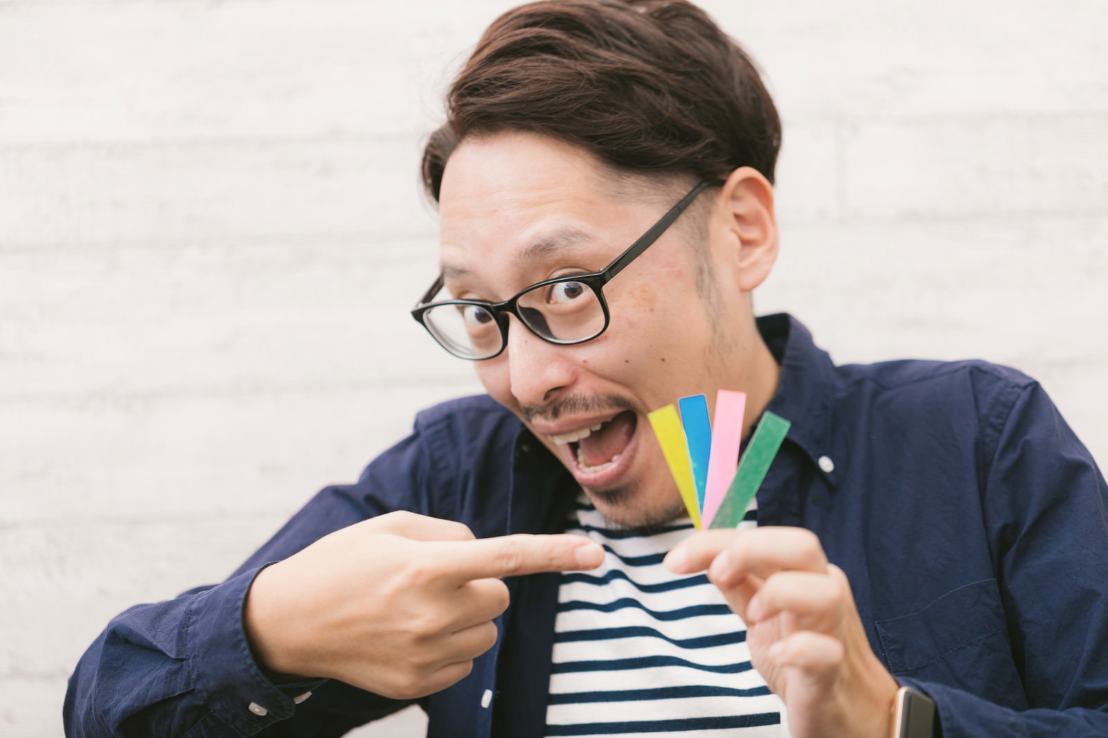眼鏡をかけた男性が商品を手に持ち興奮した表情で説明している［モデル：ゆうせい］