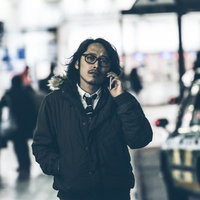 彼女との待ち合わせに向かう男性が電話で話しながら歩くの写真