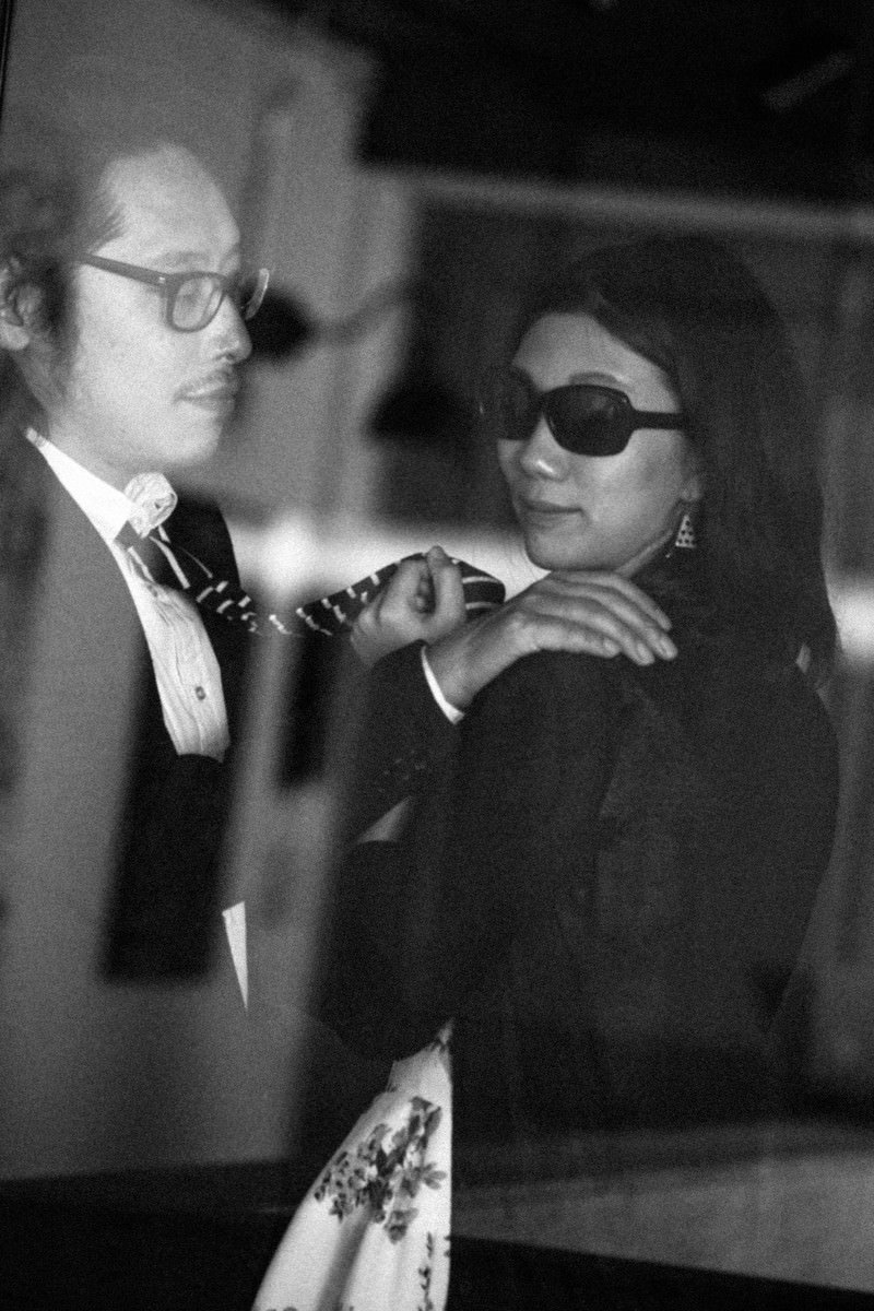 眼鏡とサングラスをかけた男女が会議室で身を寄せて向き合っている［モデル：ゆうせい］