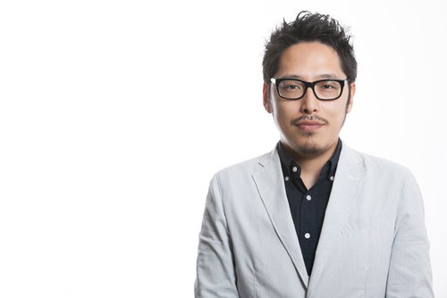 飄々と会議に遅れてきたデザイナー部長、眼鏡姿でオフィスに登場