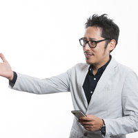 スマートフォンを持ちながら説明するプレゼンを行う男性の写真