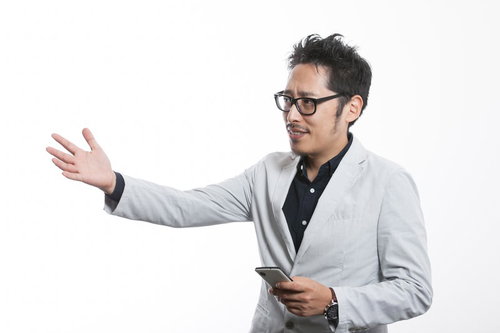 スマートフォンを持ちながら説明するプレゼンを行う男性