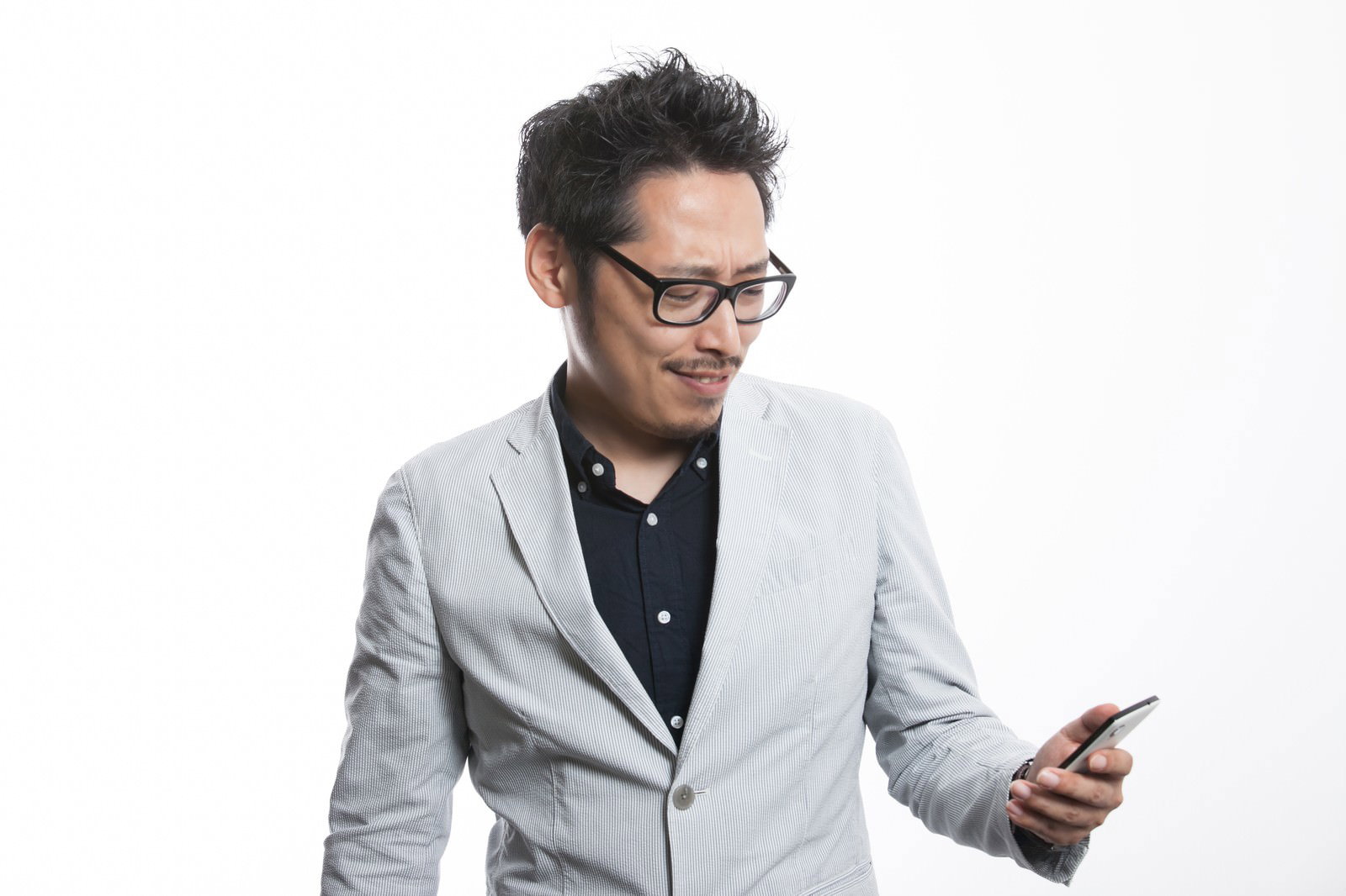 スマホでランチのメニュー情報を確認しているメガネをかけたグレージャケット姿の男性［モデル：ゆうせい］