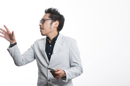 スマホを片手に熱く説明するグレーブレザーの男性社長