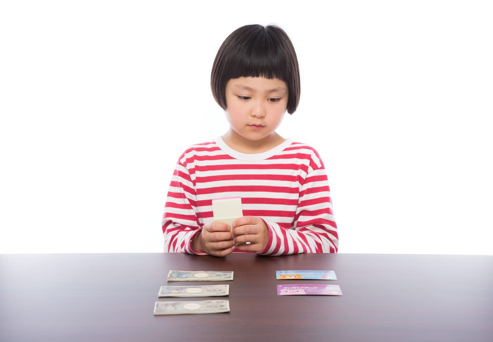 赤白ボーダーシャツの女の子が机でお札を確認している［モデル：ゆうき］